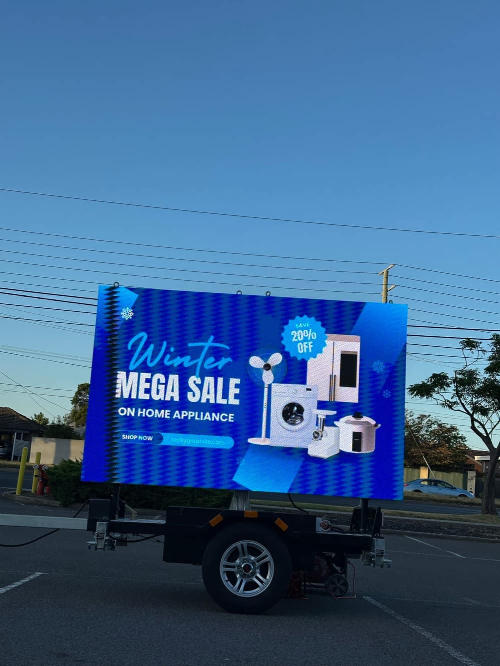 Rear three-quarter view of the LED trailer sign showing a 'Winter Mega Sale' appliance promotion with product images