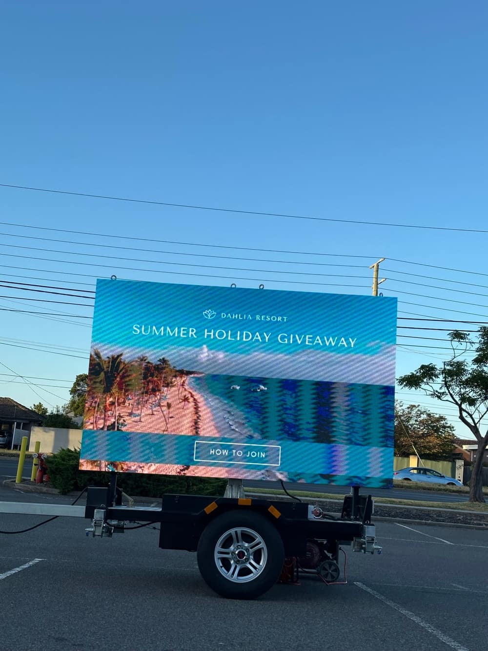 LED trailer sign showing a travel resort's 'Summer Holiday Giveaway' campaign with a beach image